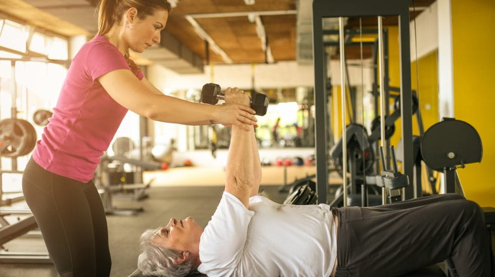 Joining a gym woman lifting weights with gym instructor